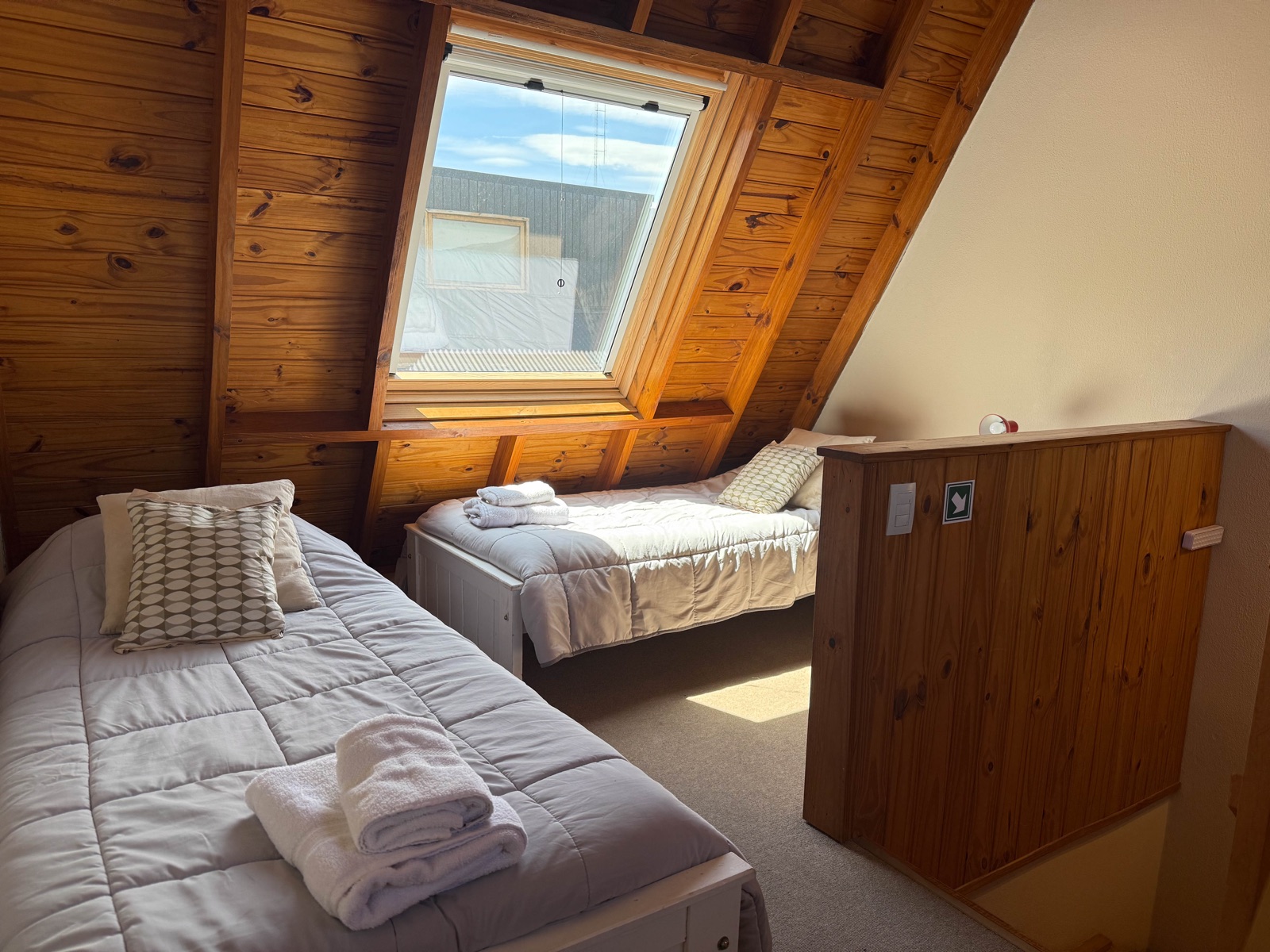 Altillo con dos camas individuales y techo inclinado de madera