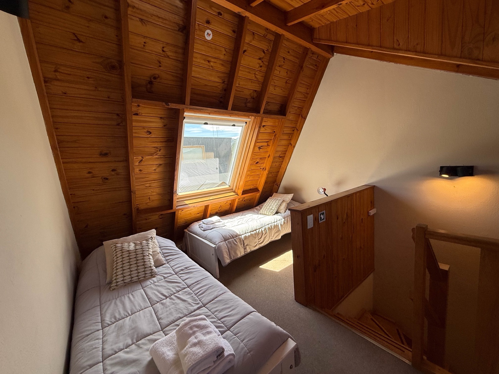 Altillo con techo inclinado de madera y dos camas